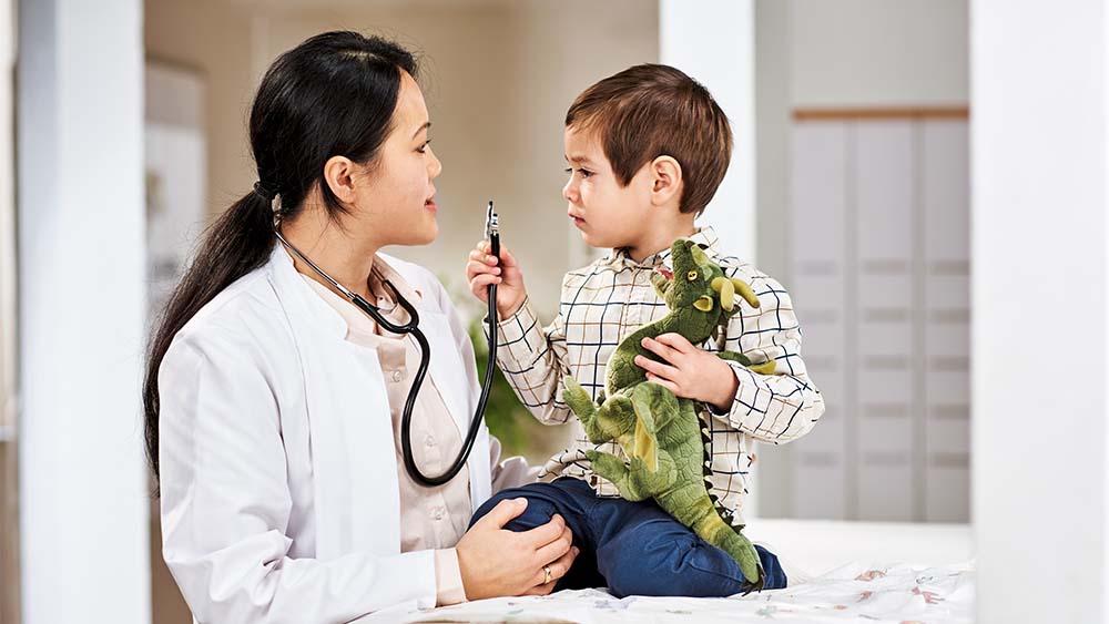 Kinderärztin spricht mit jungem Patienten auf Augenhöhe