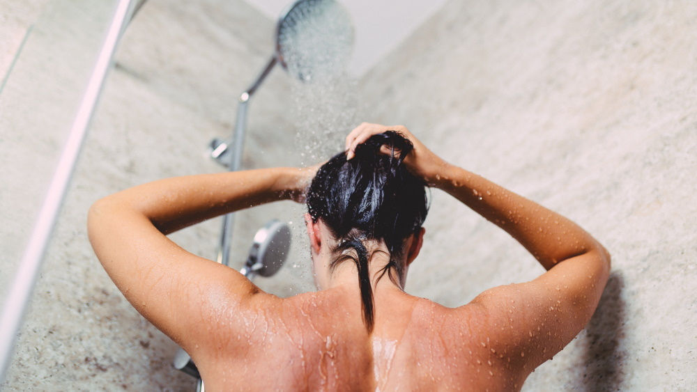 Eine Frau steht in der Dusche unter fließendem Wasser