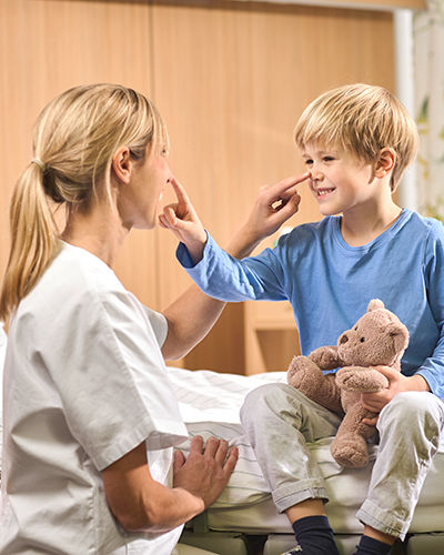 Krankenschwester und kleiner Patient klopfen sich spielerisch auf die Nasenspitze