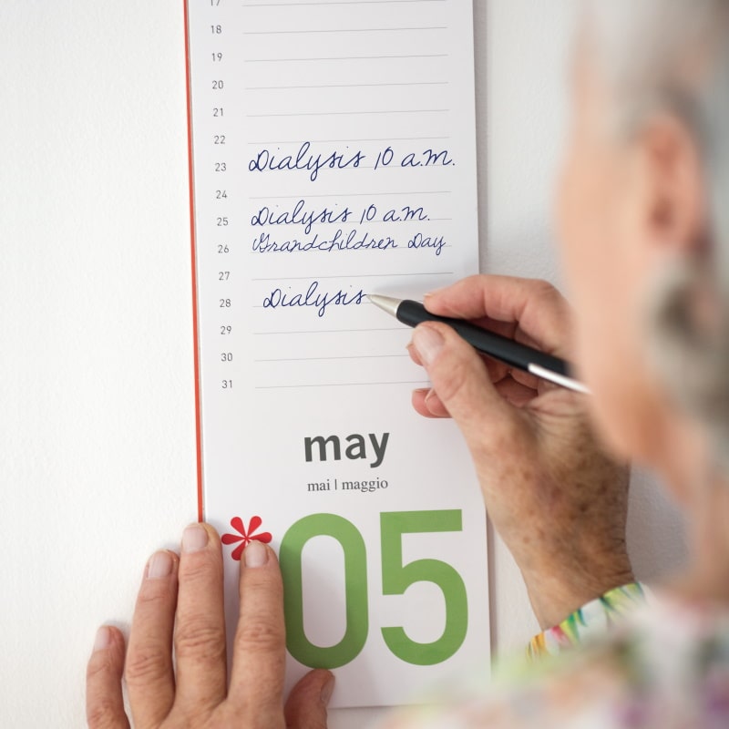 Ältere Frau macht sich Notizen in ihrem Kalender