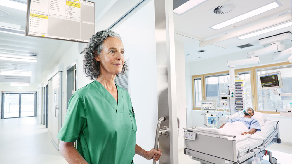 Pflegekraft betritt Intensivpatientenzimmer mit priorisierter Alarmbehandlung