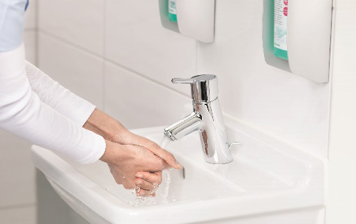 Weibliche Hände unter einem Wasserstrahl am Waschbecken
