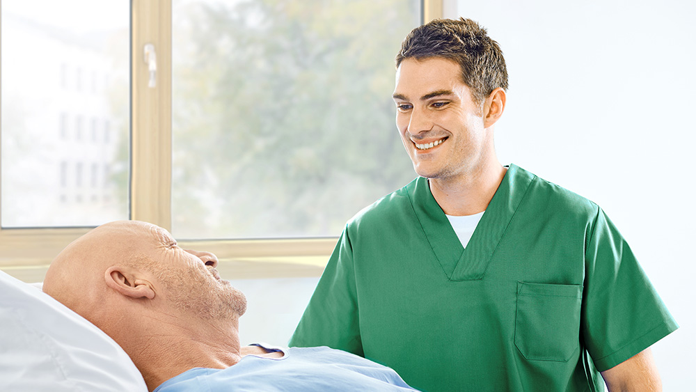 Eine Pflegekraft spricht mit einem Patienten am Bett