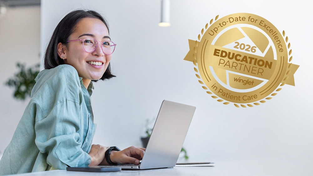 Person, die an einem Laptop an einem Schreibtisch arbeitet, daneben ein goldenes Abzeichen, das die Winglet Education Partnerschaft repräsentiert
