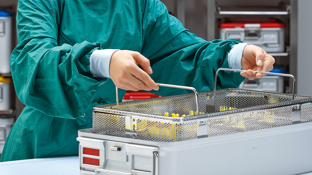Mitarbeiter der AEMP hebt einen Korb mit Instrumenten aus einem Sterilcontainer