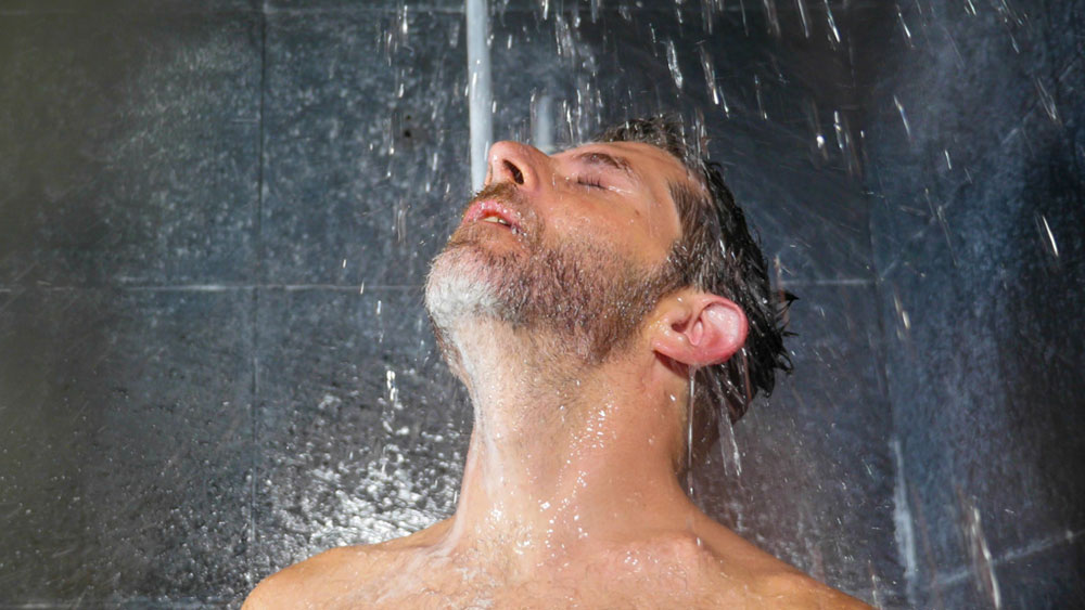 Ein Mann steht in der Dusche mit fließendem Wasser
