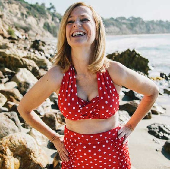 Frau am Strand, lachend in rotem Bikini mit weißen Punkten